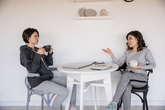 Two people sitting at a table having a casual conversation over coffee